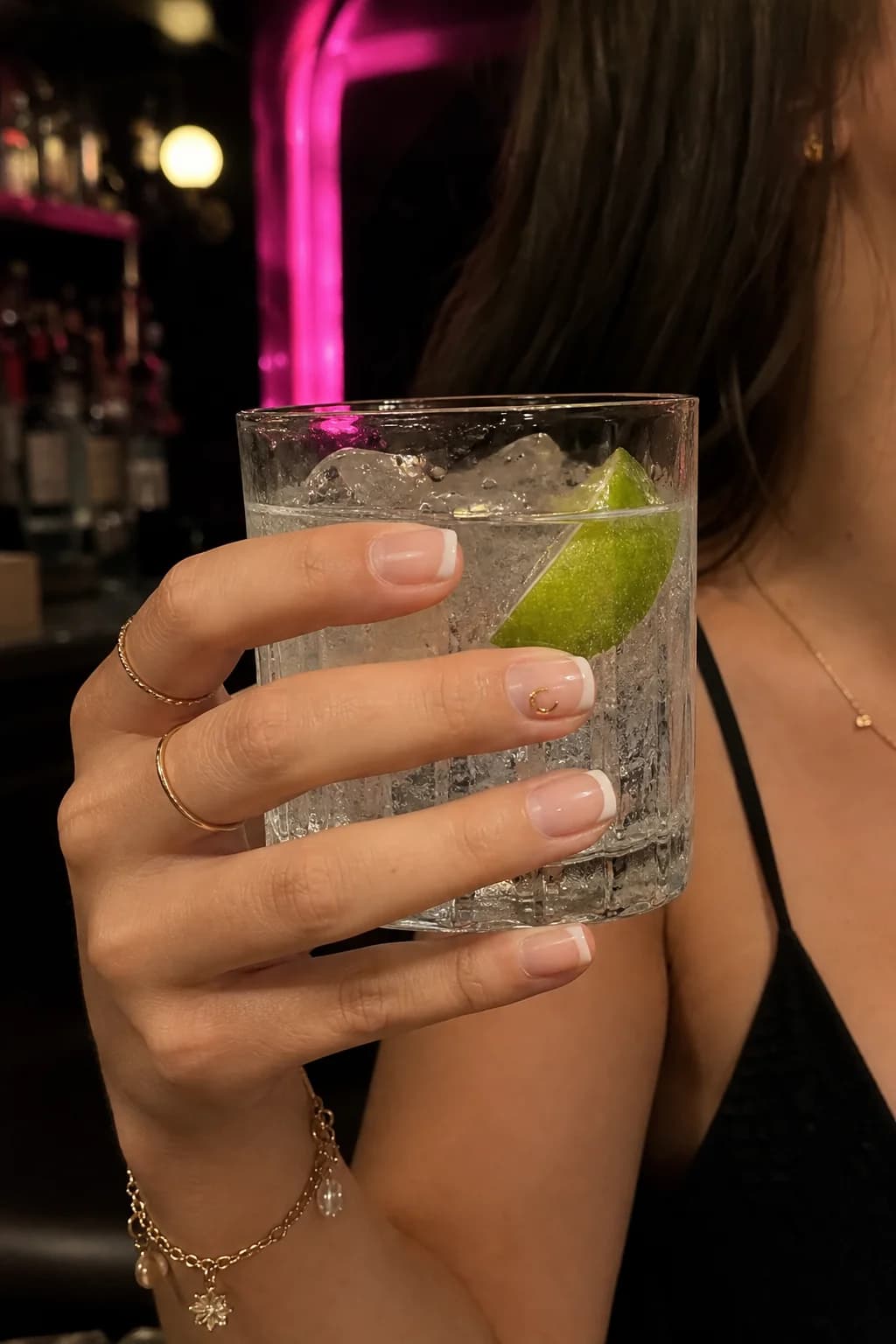 French manicure with the Vesper crescent sticker, holding a gin and tonic at the bar